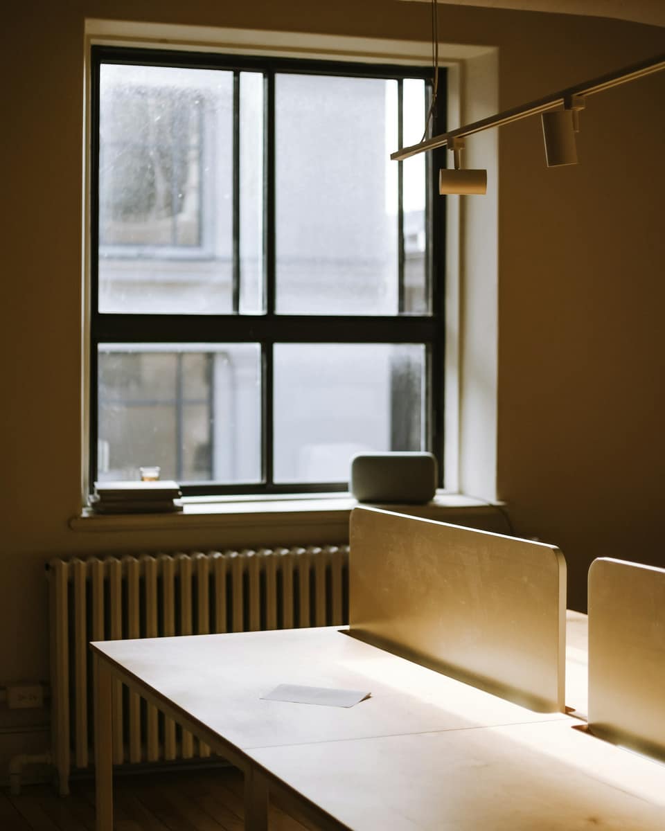 Warm-lit desks beside a tall window in an old office building
